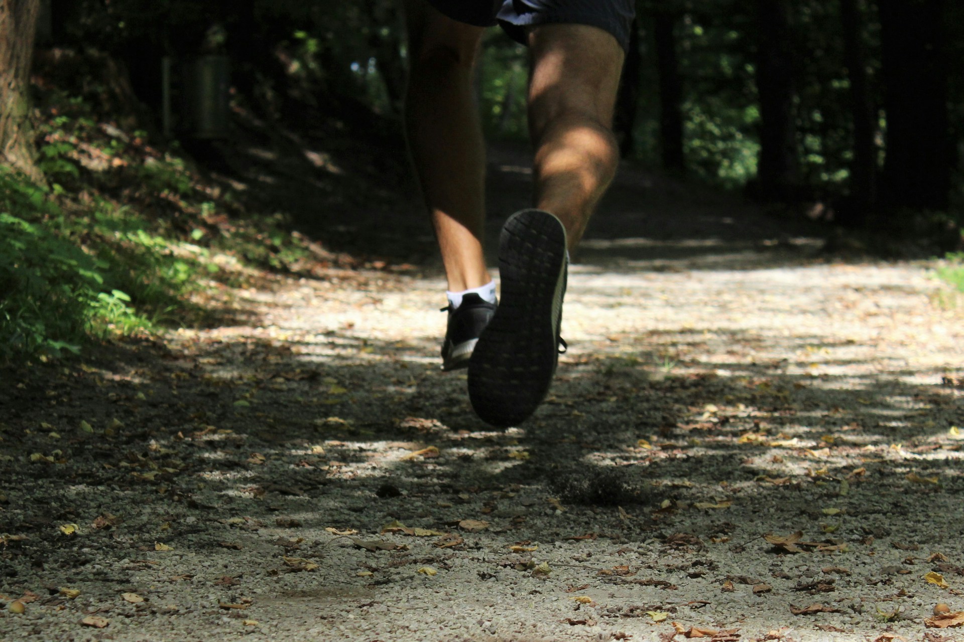 Jambes d'homme courant sur un chemin dans la forêt (course à pied)